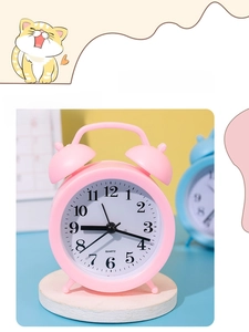 Detail of pink mini alarm clock with dual-bell design and quartz movement on tray
