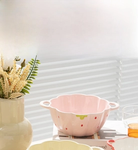 Close-up of pink and yellow ceramic strawberry bowls with double handles for soup