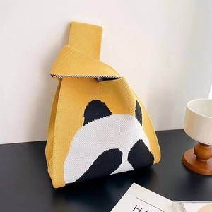 Handmade knitted yellow handbag featuring a cute panda pattern and woven wrist strap
