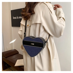 Detail of heart-shaped denim crossbody bag showing adjustable strap and zipper texture
