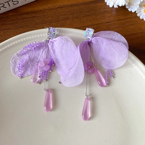 Detail of purple chiffon petal earrings with beads and water drop pendants in a ceramic tray