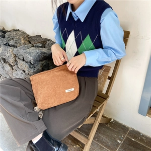 Casual lifestyle shot of a brown corduroy clutch bag with a textured striped finish