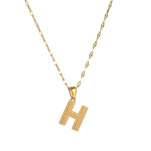 Close-up of golden stainless steel necklace with textured letter H alphabet pendant