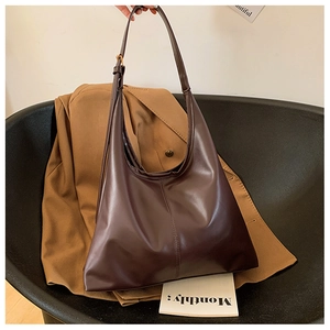 Detail of dark brown leather hobo bag with adjustable strap on a camel blazer