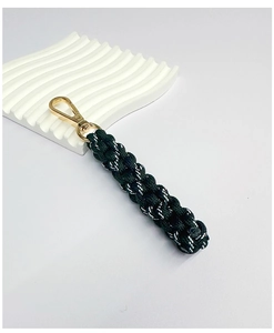 Close-up of black braided paracord keychain with premium gold metal clasp on stone tray