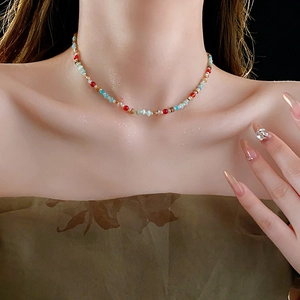 Close-up of a colorful beaded necklace with blue and gold accents on a model's neck