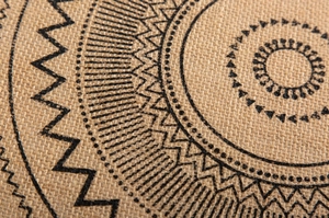 Macro detail of hand-woven jute placemat with black geometric pattern and rustic texture