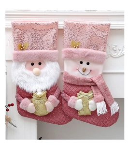 Rosafarbene Weihnachtssocken mit Weihnachtsmann und Schneemann-Pailletten am Kamin