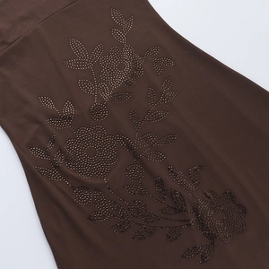 Detail of floral patterns made of dark rhinestones on soft brown vacation dress fabric