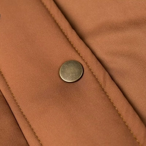 Makroaufnahme von Bronze-Druckknopf und Nähten an einer braunen Vintage-Baseballjacke