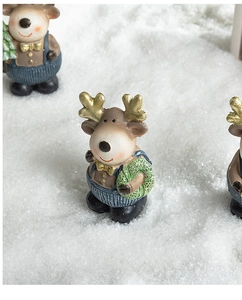 Christmas resin reindeer figurines with golden antlers on an artificial snow background