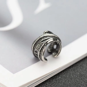 Macro detail of retro silver feather ear cuff with adjustable open-ring design and textures