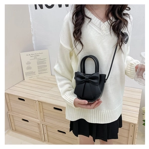 Close-up of black crossbody bag featuring a large bow detail and elegant round handle