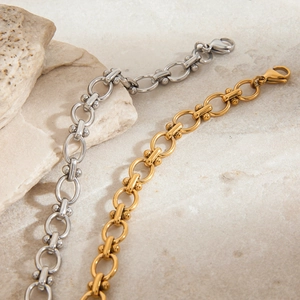 Polished gold and silver O-link chain bracelets with metal beads on marble display