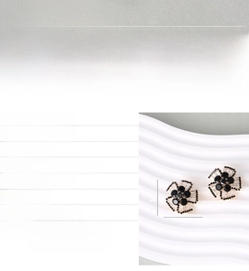Detailed macro view of black zircon flower earrings with white petals on a display stand