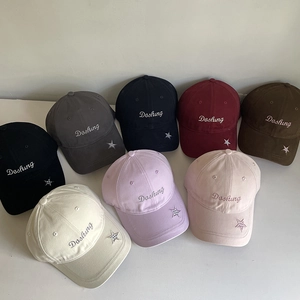 Detail showing various colors of cotton baseball caps with star patch and embroidery