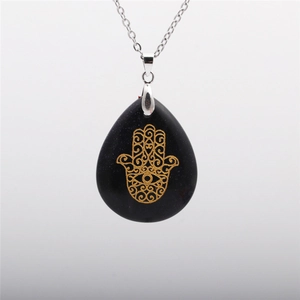 Detailed view of water drop blue sandstone pendant with golden Hamsa Hand on silver chain