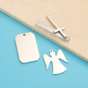 Macro detail of silver stainless steel angel, cross and square pendant charms for jewelry
