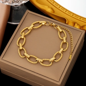 Elegant gold oval twisted chain bracelet on a brown jewelry box background