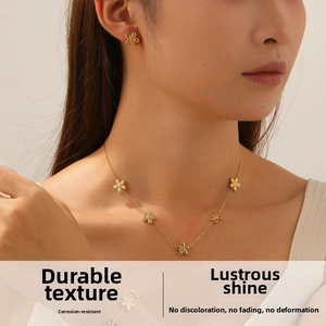 Detail view of a gold-plated stainless steel jewelry set with five-petal flower motifs