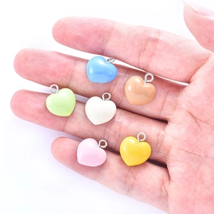 Hand holding colorful resin heart charms to show size for DIY jewelry making