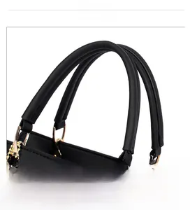 Close-up of black leather handbag featuring round handles and golden D-ring hardware