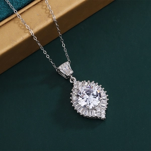 Macro detail of pear-shaped pendant with round central gemstone on a green velvet box