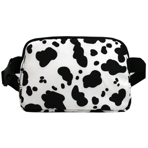 Detail of a cow print waist bag showing the zipper and black adjustable nylon strap