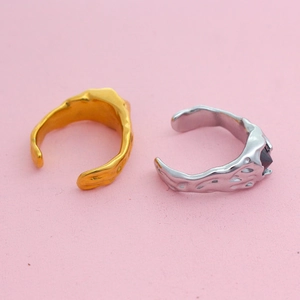 Detail view of gold and silver melting texture rings with black zircon on pink background