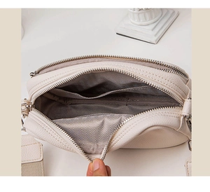 Interior detail of creamy leather shoulder bag featuring multiple compartments and woven strap