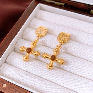 Close-up of vintage gold cross earrings with amber gemstone set in a jewelry box