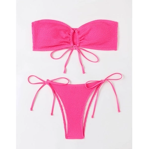 Flat lay of neon pink bandeau bikini featuring ribbed texture and side-tie details