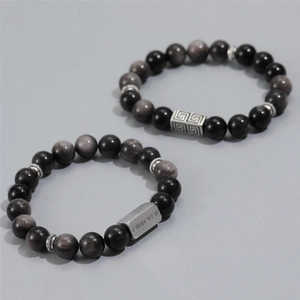 Close-up of black obsidian beaded bracelet with silver metal tag engraved with FOREVER