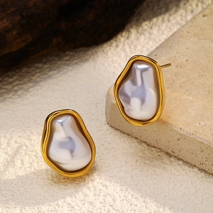 Close-up of gold plated stainless steel stud earrings with irregular pearl inlay