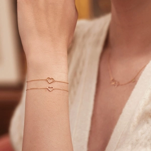 Detailed view of an S925 silver heart bracelet in gold finish worn on a model's wrist