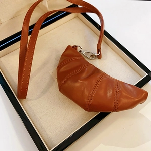Makroaufnahme der braunen Kunstleder-Croissant-Tasche im minimalistischen Display-Kasten
