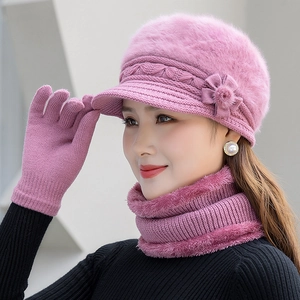 Detailed view of pink knitted winter set including hat with floral decor, scarf and gloves