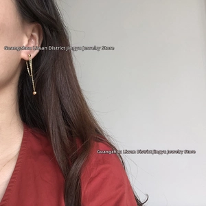 Minimalist gold chain drop earrings with spherical beads worn by a model in a side view