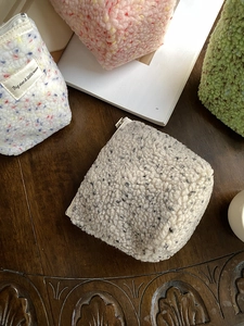Vista dall'alto di quattro pochette in peluche nei colori grigio, rosa, bianco e verde