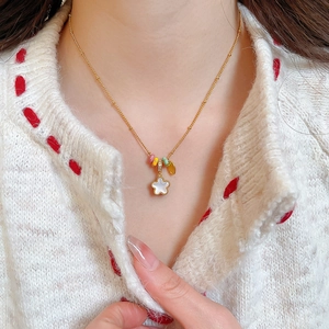 Close-up of elegant gold flower necklace with white shell pendant on female neck