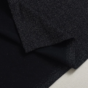 Detailed close-up of the black glitter fabric with silver sparkles and hemline stitching