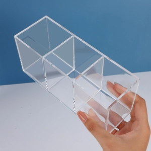Transparent 3-slot acrylic makeup brush organizer box being held by hand with blue background