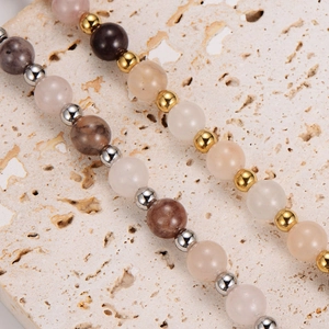 Pink and brown agate beaded necklace with metallic spacers on a travertine surface
