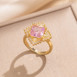 Macro shot of gold ring with square pink gemstone and sparkling zircon halo