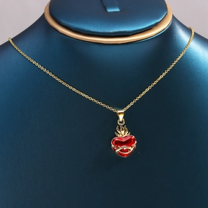 Gold necklace with red heart pendant featuring thorn vine pattern on a display stand