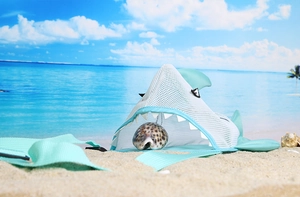 Detail of light blue shark mesh bag for shells on beach with sea background