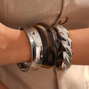 Three-piece stackable bracelet set featuring silver metal and brown resin on a model arm