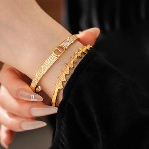 Close-up of gold-plated bangle featuring crystal pave fan-shaped and D-letter designs