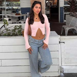 Close-up of pink knit cropped cardigan with button-front design and long sleeves