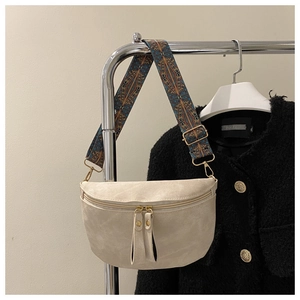 Détail du sac beige avec bandoulière géométrique colorée et fermetures éclair en métal